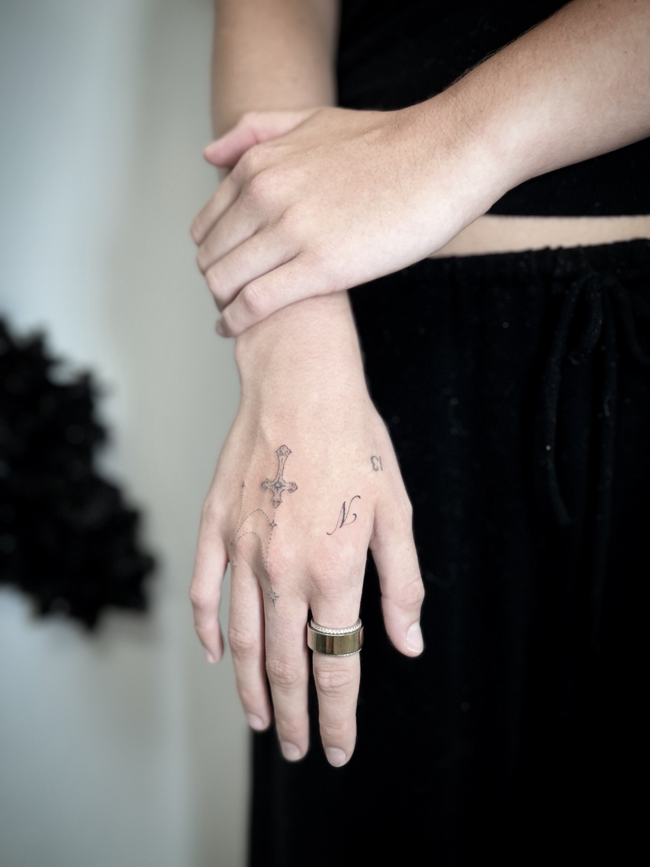 Fine line cross and rosary hand tattoo